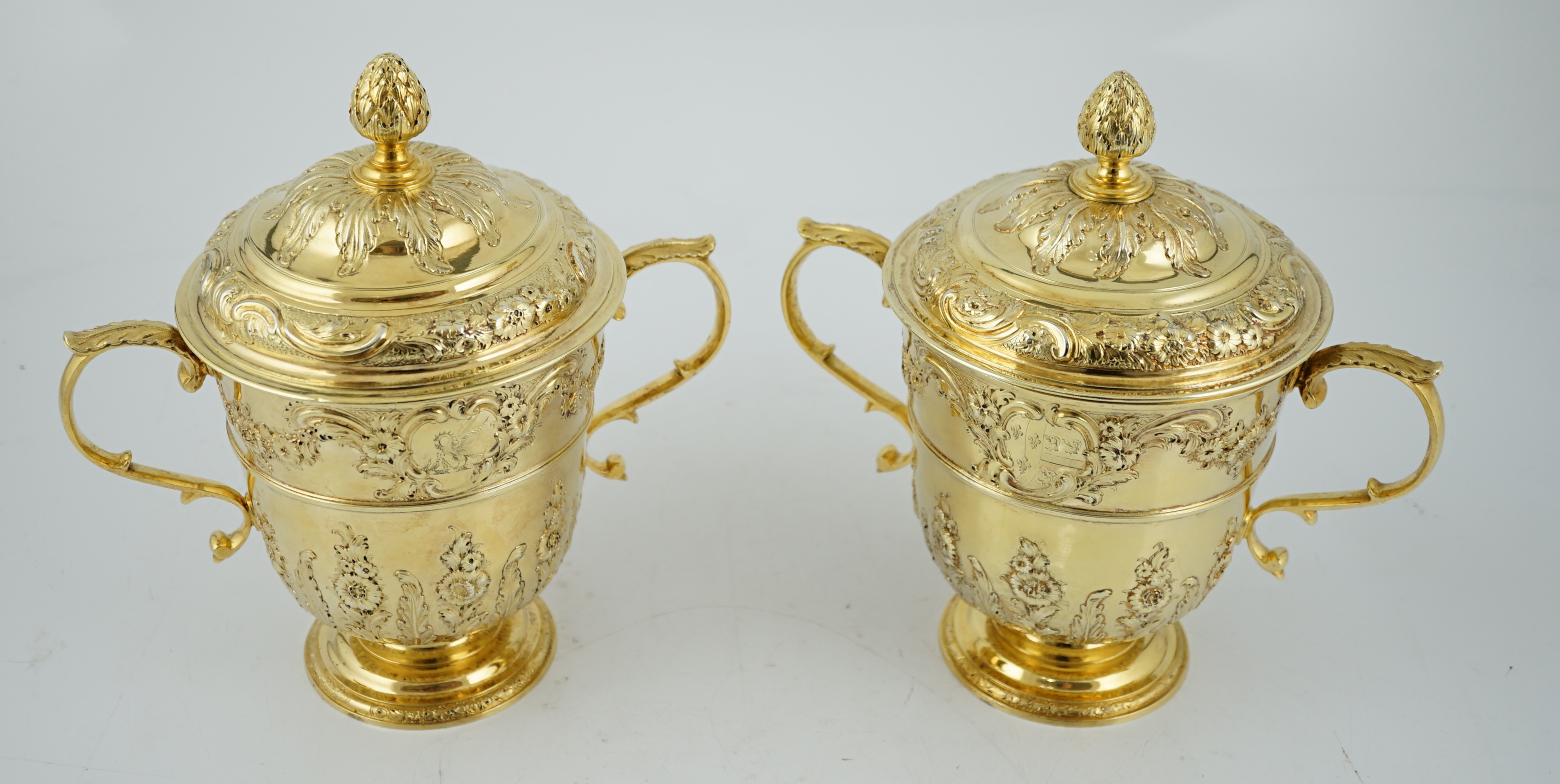 Benacre Hall, Suffolk. A good pair of George II embossed silver gilt two handled pedestal cups and covers, by Benjamin Gignac